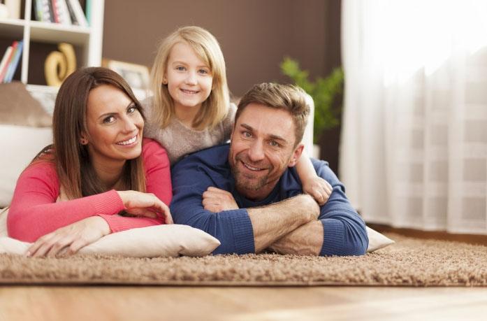 Family of three laying on carpet in living room