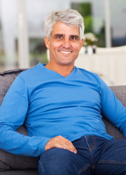 Man in blue shirt smiling with dentures in Oklahoma City