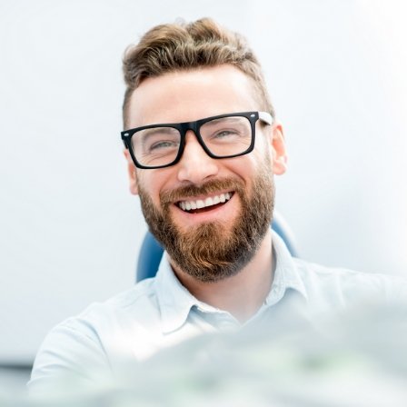 Man with beard and glasses smiling in dental chair