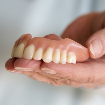 Hand holding a full denture