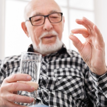 Man holding pill and glass of water